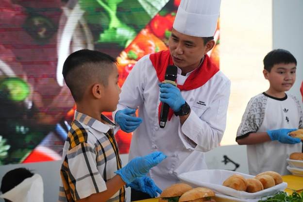 Chef tận tình hướng dẫn bé làm bánh mỳ. (Ảnh: VNA). Chef tận tình hướng dẫn bé làm bánh mỳ. (Ảnh: VNA).