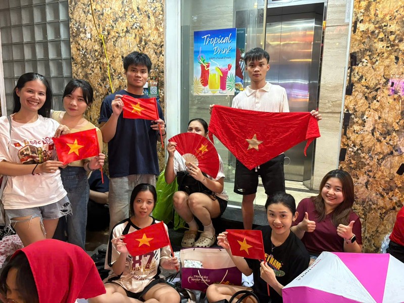 Chị Nhật Lệ (ngoài cùng bên phải) cùng gia đình, bạn bè đã chuẩn bị những hành trang cần thiết để chờ đợi xem buổi Tổng duyệt diễu binh, diễu hành sáng mai. Ảnh: Bảo Trâm. C3.jpg