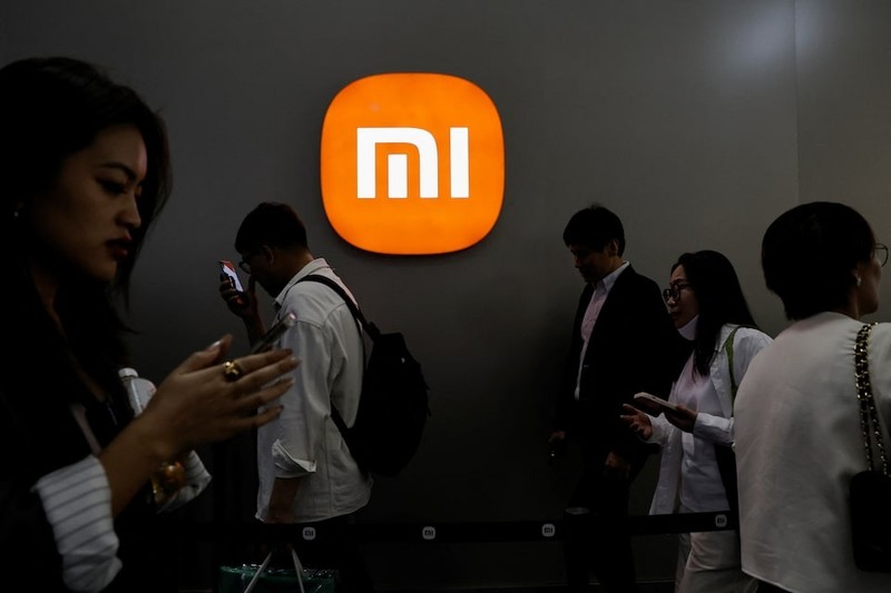 Khách tham quan đi ngang qua logo Xiaomi tại Triển lãm ô tô quốc tế Bắc Kinh 2024. Ảnh: Reuters Xiaomi - Reuters.jpg