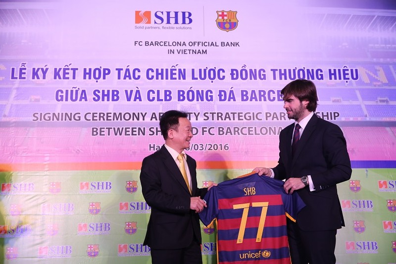 Ông Xavier Asensi - Giám đốc Điều hành khu vực Châu Á Thái Bình Dương CLB Barcelona (bên phải) tặng quà lưu niệm cho Ông Đỗ Quang Hiển - Chủ tịch HĐQT SHB, chiếc áo mang số 77 – là địa chỉ Trụ sở chính của SHB trên phố Trần Hưng Đạo