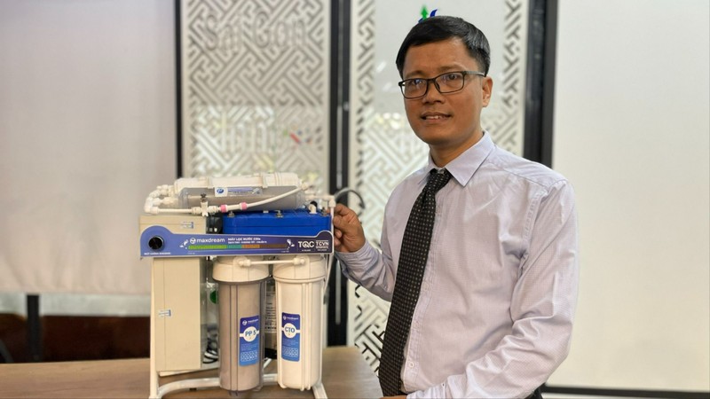 TS Đỗ Hữu Quyết bên cạnh sản phẩm máy lọc nước sử dụng công nghệ CDI do mình chế tạo. Ảnh: Hà An. TS loc nuoc.jpg