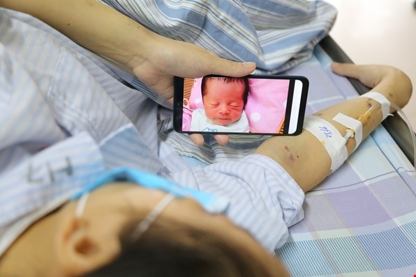 Chị Vang ngắn nhìn đứa con thơ qua màn hình điện thoại trong lúc điều trị. Chị Vang ngắn nhìn đứa con thơ qua màn hình điện thoại trong lúc điều trị.
