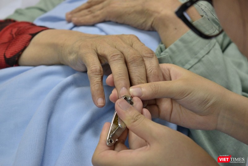 Một nữ điều dưỡng tỉ mẩn cắt móng tay cho bệnh nhân. Một nữ điều dưỡng tỉ mẩn cắt móng tay cho bệnh nhân.