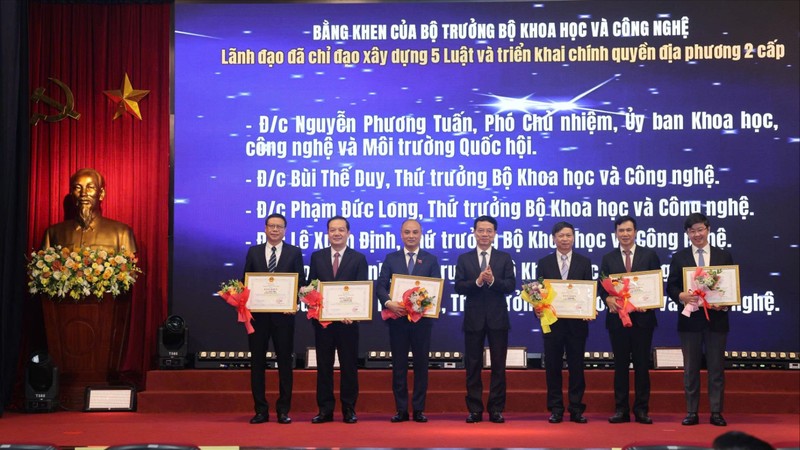 Bộ trưởng Nguyễn Mạnh Hùng trao tặng Bằng khen cho các lãnh đạo đã chỉ đạo xây dựng 5 luật và triển khai chính quyền địa phương hai cấp. Ảnh: T.H z6802908776038_041820bf95f48ea8152f066c867d669f.jpg