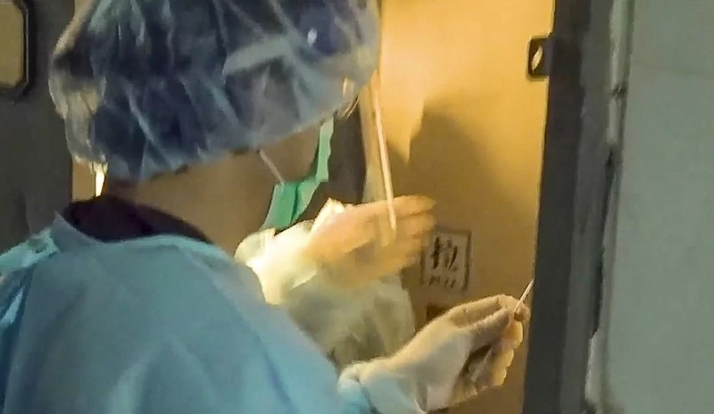 Nhân viên y tế lấy mẫu xét nghiệm tại Phòng tiệc Lento, Kwun Tong, nơi gia đình nọ tổ chức tiệc lẩu (Ảnh: SCMP)