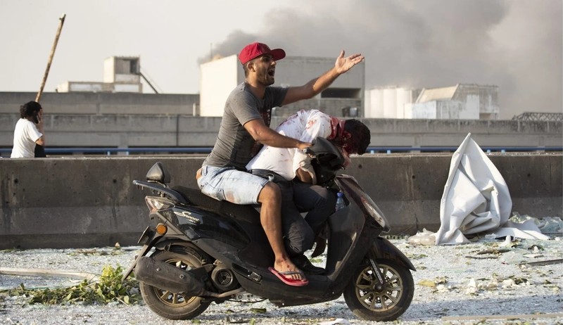 Một người đàn ông cứu giúp người bị thương sau vụ nổ ở Beirut (Ảnh: AP)