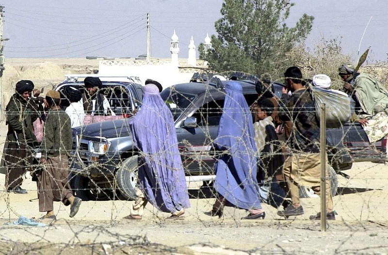Những người phụ nữ Afghanistan phải phủ Burqa kín mít đi ngang qua các tay súng Taliban, năm 2001 (Ảnh: AFP) Những người phụ nữ Afghanistan phải phủ Burqa kín mít đi ngang qua các tay súng Taliban, năm 2001 (Ảnh: AFP)