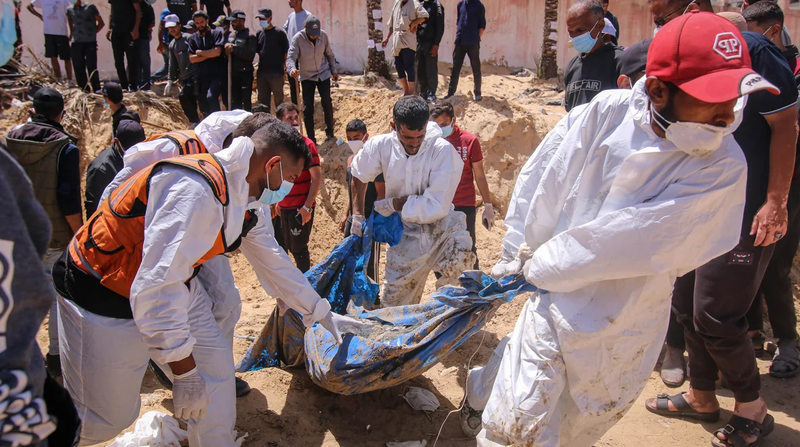 Nhân viên y tế Palestine kéo các thi thể bị chôn vùi từ một ngôi mộ tập thể tại khu liên hợp Y tế Nasser ở Khan Younis, Gaza vào ngày 21/4 (Ảnh: Getty)