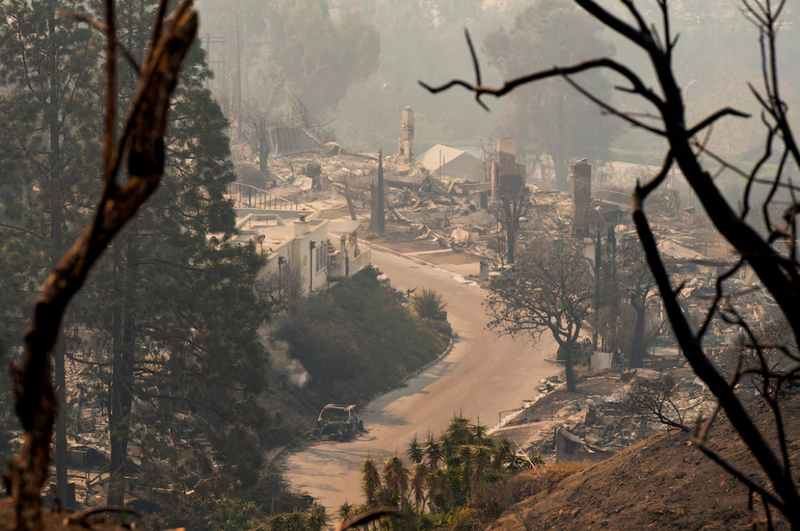 Một chiếc ô tô bị cháy nằm giữa tàn tích của những ngôi nhà sau vụ cháy Palisades ở khu Pacific Palisades, Los Angeles, California, Mỹ. Ảnh: Reuters.