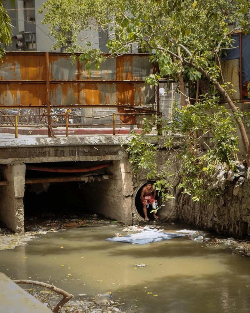 Một người đàn ông trèo ra khỏi cống ở một con lạch tại thành phố Makati, nơi có một cộng đồng nhỏ những người sống lang thang ở Philippines. Ảnh: William Roberts. Người chui cống giữa trung tâm tài chính Sự thật gây sốc về người vô gia cư ở Philippines 2.jpg