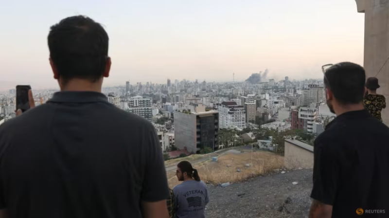 Mọi người xem khói bốc lên sau cuộc tấn công của Israel vào tòa nhà IRIB, đài truyền hình nhà nước của nước này, tại Tehran, Iran vào ngày 16/6. Ảnh: Reuters. Iran cảnh báo hậu quả không thể đảo ngược sau khi ông Trump dọa loại bỏ lãnh tụ tối cao 3.png