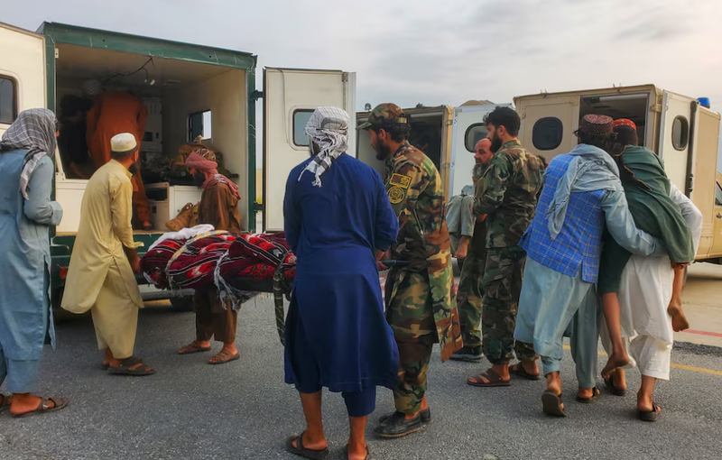 Binh lính Taliban và thường dân đưa nạn nhân động đất lên xe cứu thương tại sân bay ở Jalalabad, Afghanistan ngày 1/9. Ảnh: Reuters.