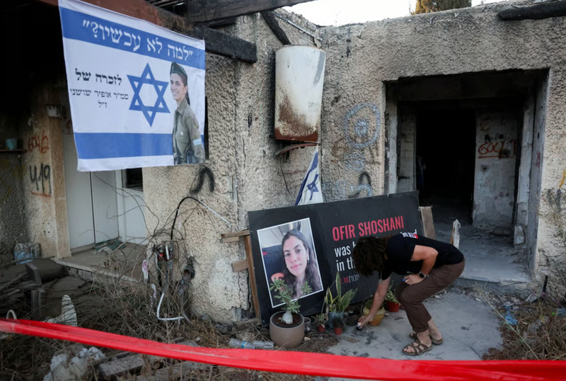 Một người dân của cộng đồng kibbutz Kfar Aza đặt một ngọn nến để tưởng niệm nạn nhân trong vụ tấn công 7/10/2023. Ảnh: Reuters. Ông Trump, ông Netanyahu và ván bài cuối ở Trung Đông Liệu Gaza có thể im tiếng súng 4.png