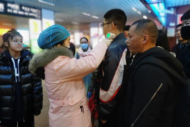 Một nhân viên kiểm tra nhiệt độ cơ thể của hành khách khi họ đến ga xe lửa ở thành phố Yingtan, tỉnh Giang Tây, Trung Quốc. Ảnh: EPA-EFE