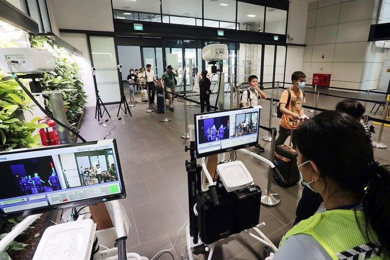 Nhân viên kiểm tra thân nhiệt tại sân bay. Ảnh: KELVIN CHNG Nhân viên kiểm tra thân nhiệt tại sân bay. Ảnh: KELVIN CHNG