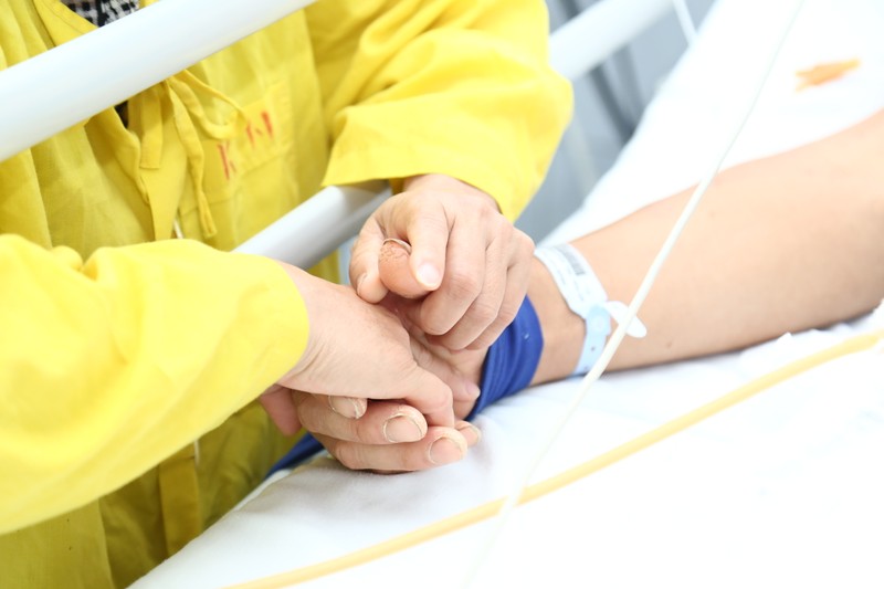 Chị Mính nắm chặt tay chồng trên giường bệnh. Ảnh: BVCC Chị Mính nắm chặt tay chồng trên giường bệnh. Ảnh: BVCC