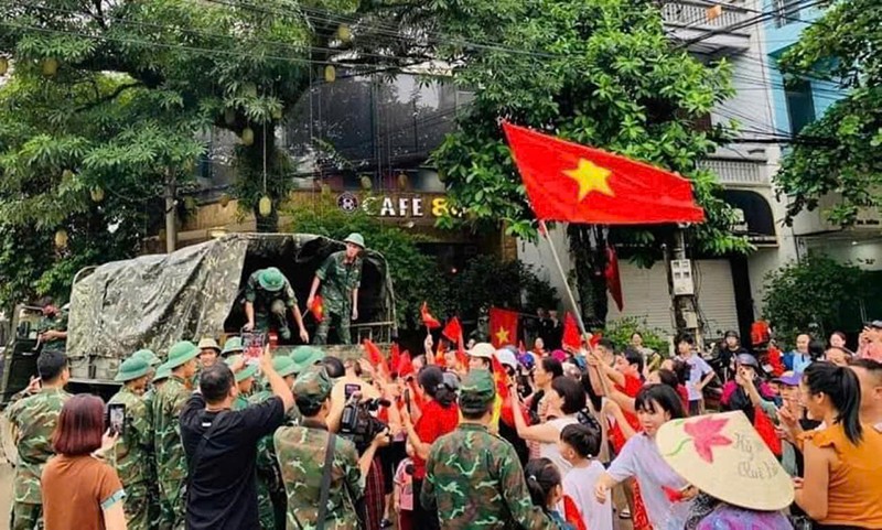 Người dân mang cờ, hoa ra chào các chú bộ đội. (Ảnh: Cổng thông tin điện tử tỉnh Yên Bái). Anh 1.jpg