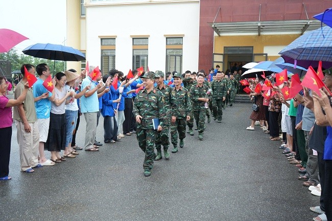 Người dân cầm cờ, hoa vẫy tay chào tạm biệt lực lượng quân đội. (Ảnh: Cổng thông tin điện tử huyện Trấn Yên) Anh 2.jpg