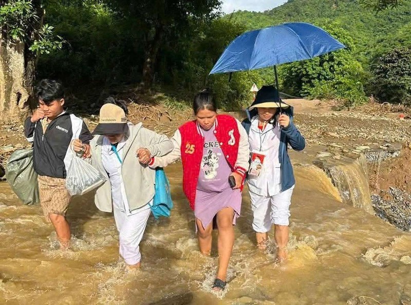 Nhân viên y tế hỗ trợ sản phụ vượt lũ đi sinh. Ảnh: Vi Ngọc Mai. Anh 1.jpg