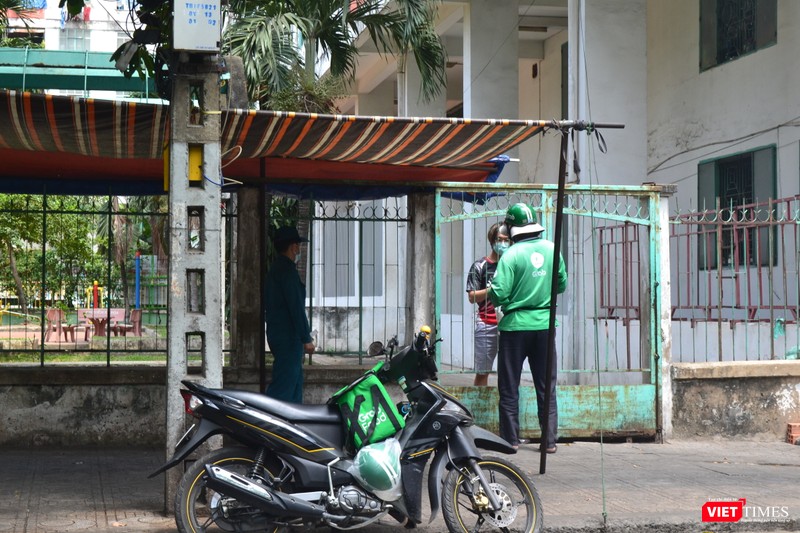 Một người dân trong chung cư đặt cơm trưa, có lực lượng an ninh theo sát. Ảnh: Nguyễn Trăm