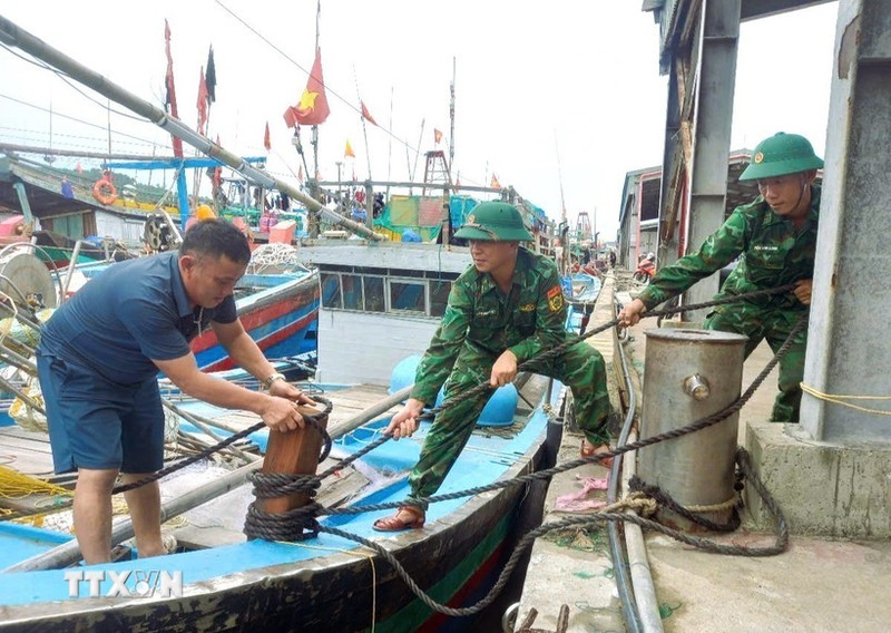 Lực lượng Bộ đội biên phòng tỉnh Nghệ An hỗ trợ giúp ngư dân chằng néo tàu thuyền tại nơi tránh trú bão an toàn. (Ảnh: TTXVN phát) 21-7. jpg bao-so-3.jpg