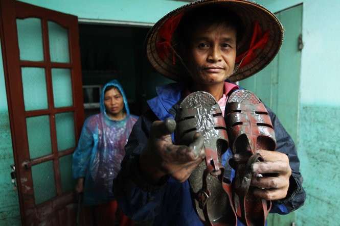 Ông Tô Văn Thắng cầm trên tay đôi dép của một chiến sĩ trong đội cứu hộ bị rớt lại. Ông cho biết nếu không có sự quả cảm, kịp thời của những người lính thì vợ chồng ông có thể bị chết khi nước lũ dâng cao đột ngột.