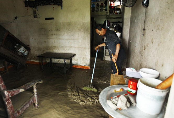 Ông Phạm Văn Toản đang cặm cụi quét bùn đất ra khỏi nhà, hiện tại nước tại đây vẫn chưa rút.