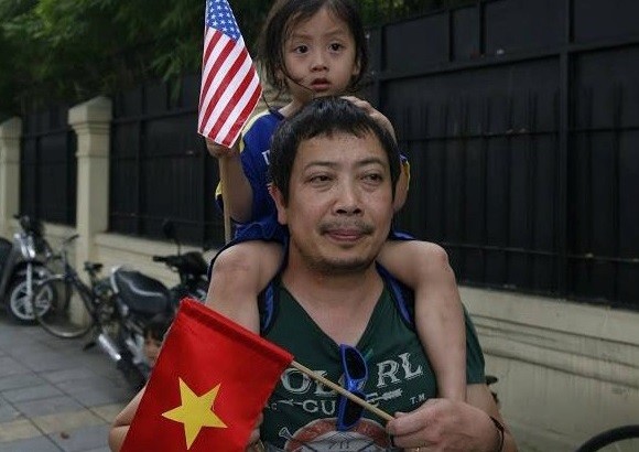 Mỹ tuyên bố dỡ bỏ hoàn toàn lệnh cấm vận vũ khí với Việt Nam ảnh 20 Em bé cầm cờ Mỹ và Việt Nam được bố đưa đi đón đoàn của tổng thống Obama. Trong khi đó, người dân đã dừng trên cầu vượt Kim Mã chờ đoàn xe tổng thống Mỹ qua.