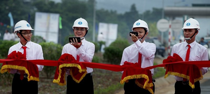 Những cán bộ ngành Giao thông tranh thủ chụp ảnh selfie bằng điện thoại thông minh trong khi đang nâng dải băng đỏ chờ cắt băng khánh thành cao tốc Nội Bài - Lào Cai vào tháng 9/2014.