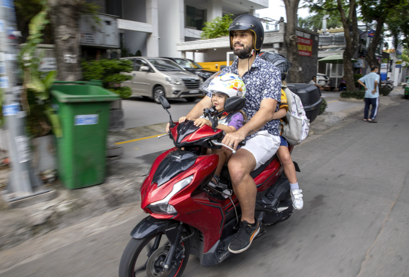 Vinnie Lauria chở con đi học bằng xe máy tại TP.HCM (Nguồn: Bloomberg)