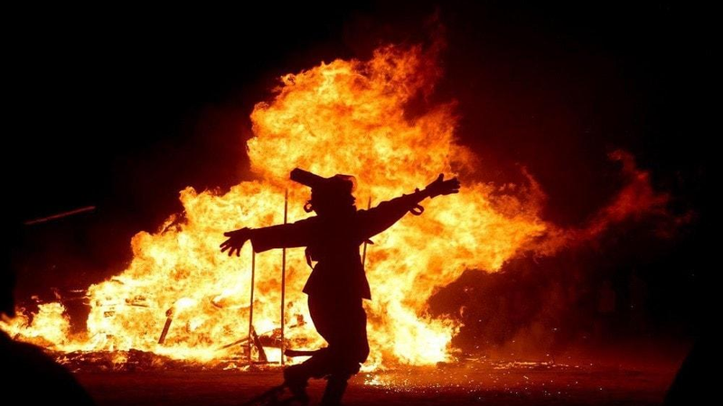 Một người đàn ông nhảy bên một đám cháy lớn trong lễ kỷ niệm lễ hội Lửa