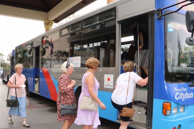 Các hành khách lên xe buýt đi tham quan thành phố Phnom Penh (Ảnh: AFP)