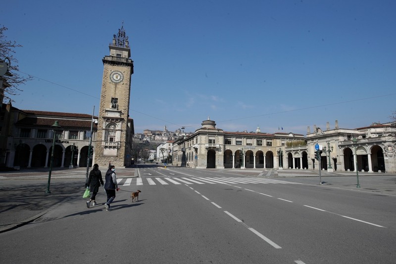 Một người phụ nữ dắt chó đi dạo trên đường phố Bergamo vào ngày 17/3 dù đã có lệnh cấm cửa (Ảnh: AP)