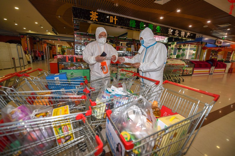 Nhân viên chống dịch kiểm tra hàng hóa các gia đình đặt mua để chuyển cho các hộ đang bị phong tỏa (Ảnh: Tân Hoa xã).