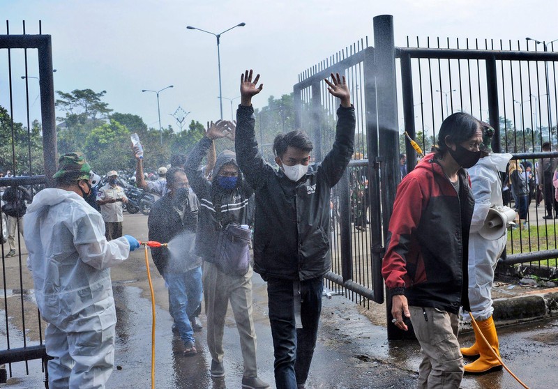 HNgày 17/6, trong đợt tiêm chủng hàng loạt ở Bandung, Tây Java, những người lính mặc quần áo bảo hộ đã phun thuốc khử trùng vào những người vào sân vận động để tiêm loại vaccine COVID-19 của Trung Quốc. (AP)