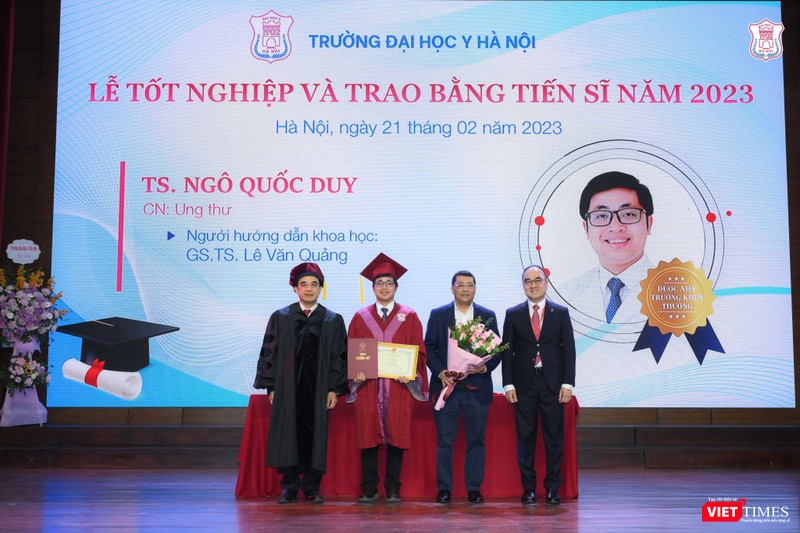 Trao bằng cho tân tiến sĩ Ngô Quốc Duy và tặng hoa giáo viên hướng dẫn nghiên cứu sinh là GS.TS. Lê Văn Quảng - Giám đốc Bệnh viện K