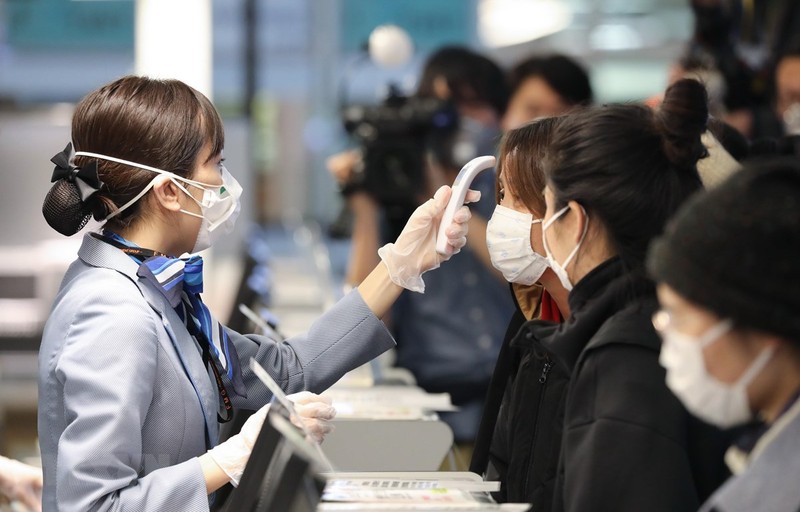 Nhân viên hàng không kiểm tra thân nhiệt các hành khách trước khi họ về Vũ Hán tại sân bay quốc tế Tokyo, Nhật Bản. (Ảnh: THX/TTXVN)