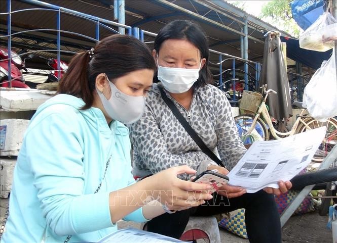 Hướng dẫn tiểu thương buôn bán tại chợ Tuy Hòa cài đặt và sử dụng ứng dụng Bluezone. Ảnh: TTXVN.
