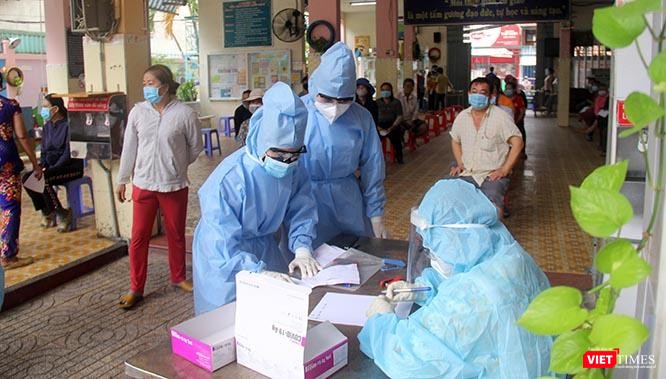 Bàn tiếp nhận phiếu ghi lấy mẫu luôn tất bật. Tất cả chỉ còn chung một màu áo xanh bảo hộ. của ngành Y. Ảnh: GVT.