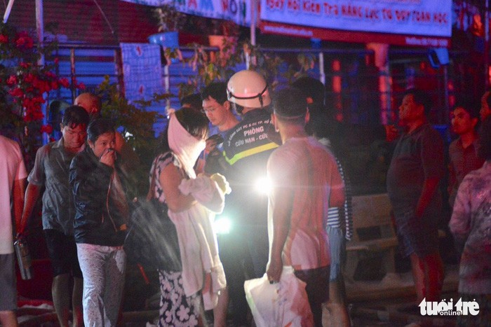 Người dân dùng khăn thấm nước thoát ra khỏi tòa nhà bị cháy lúc rạng sáng 23-3 - Ảnh: LÊ PHAN