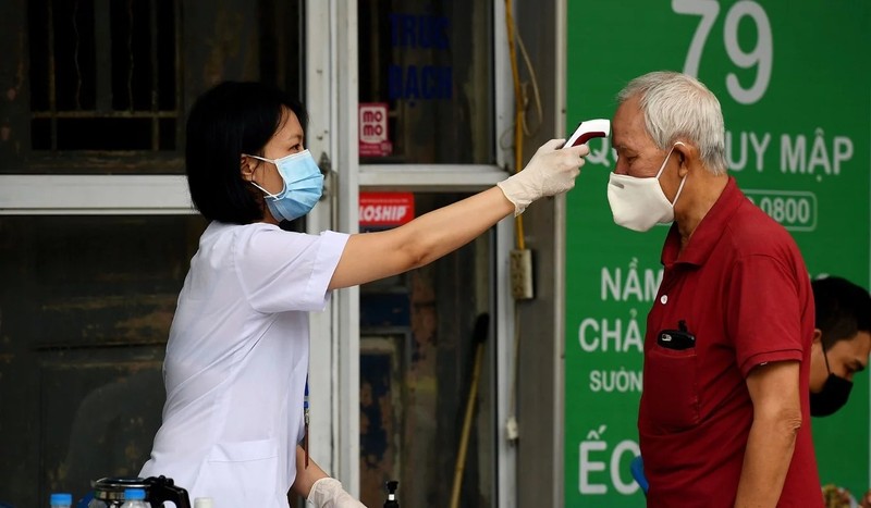 Một nhân viên y tế đeo khẩu trang kiểm tra nhiệt độ của một người đàn ông ở Hà Nội (ảnh AFP)