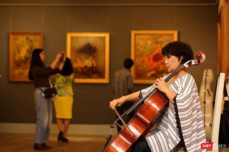 Nghệ sĩ chơi đàn tại buổi khai mạc triển lãm còn công chúng say sưa chiêm ngắm những bức tranh thuộc thể loại "nữ hoàng"