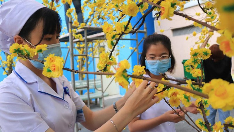 Chị Hoàng Lê Kim Ngân (cán bộ Hộ sinh, bệnh viện Từ Dũ) tranh thủ giờ nghỉ trưa xuống đường hoa phụ trang trí thêm - Ảnh KHÁNH TRẦN