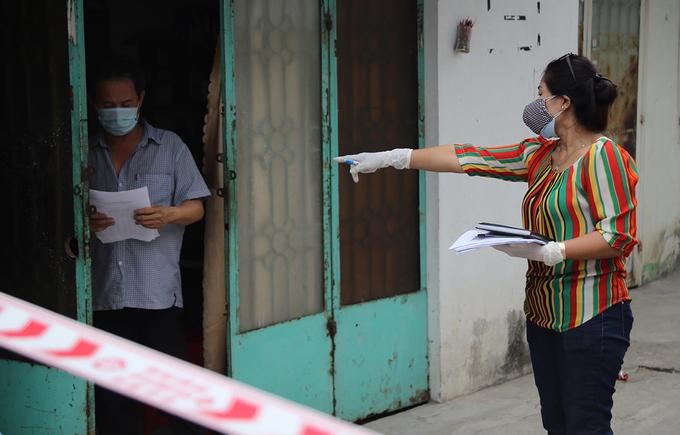 Nhân viên trung tâm y tế quận 12 đến từng hộ dân trong khu phong tỏa ở phường Thạnh Lộc, quận 12, để đưa giấy khai báo y tế, sáng 8:2. Ảnh- Đình Văn