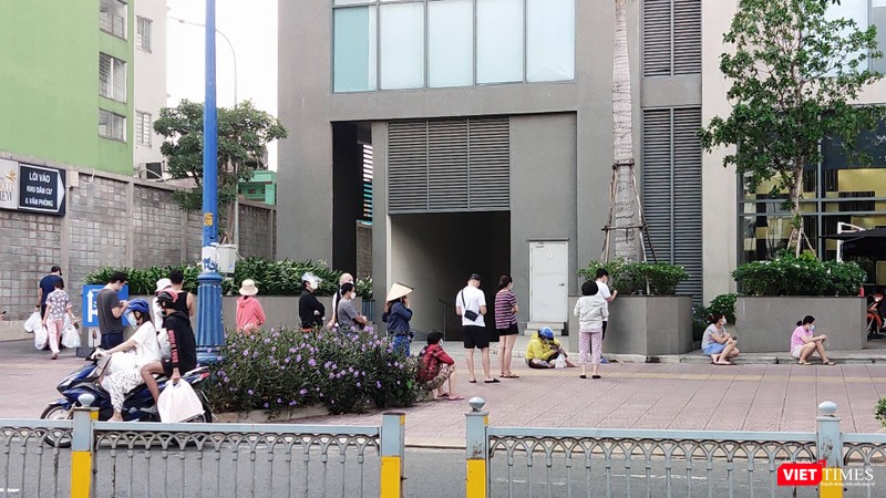 Chờ đợi quá lâu, nhiều người ngồi xuống hè phố giữa nắng trưa. Ảnh: Hoà Bình