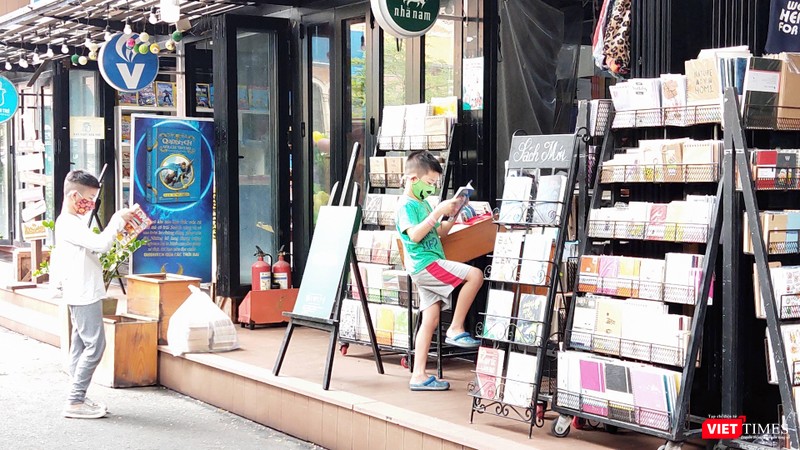 Nhiều em nhỏ say sưa đọc ngay những cuốn sách cha mẹ vừa mua tặng. Ảnh: Hoà Bình