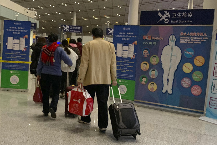 Khách du lịch đi qua một trạm kiểm tra sức khỏe trước khi nhập cảnh tại sân bay quốc tế ở Bắc Kinh (Ảnh: AP)