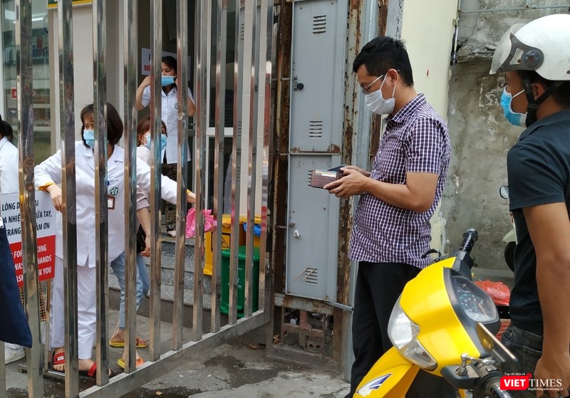 Người đàn ông áo kẻ lấy tiền để nhận số thuốc đựng trong nilon hồng từ tay nhân viên nhà thuốc tại cổng Bạch Mai trên phố Phương Mai.