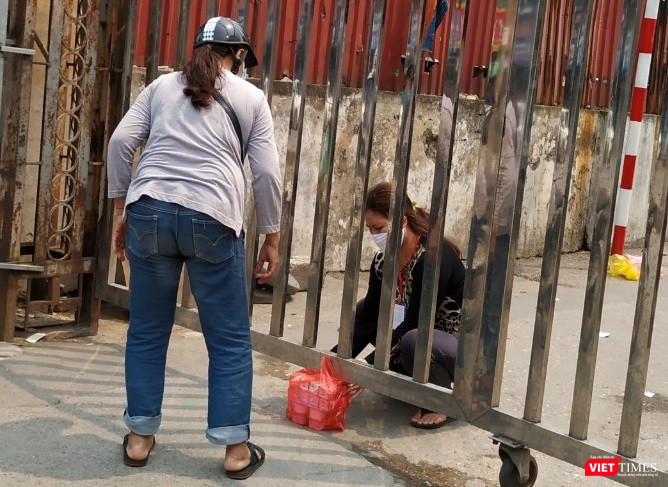 Việc tiếp tế đồ ăn tại cổng Bệnh viện Bạch Mai trên phố Phương Mai vẫn diễn ra trước sự chứng kiến của bảo vệ. Ảnh: Anh Lê.