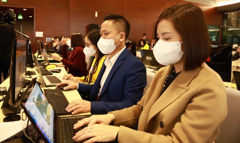 Các phóng viên thực hiện biện pháp phòng, chống dịch khi tác nghiệp tại Trung tâm Báo chí - Đại hội Đảng XIII.